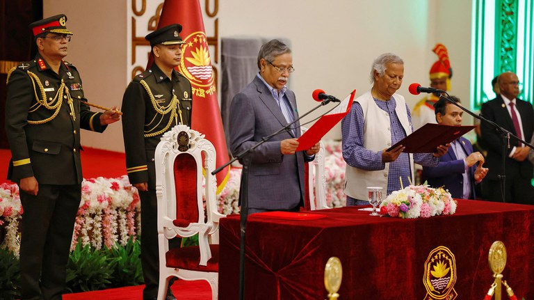 ငြိမ်းချမ်းရေးနိုဘယ်ဆုရှင် မိုဟာမက် ယူနွတ်သည် အိမ်စောင့်အစိုးရ ခေါင်းဆောင်အဖြစ် ၂၀၂၄ ခုနှစ် သြဂုတ် ၈ ရက်နေ့က ကျမ်းသစ္စာကျိန်ဆိုနေစဉ်။ Photo : Reuters