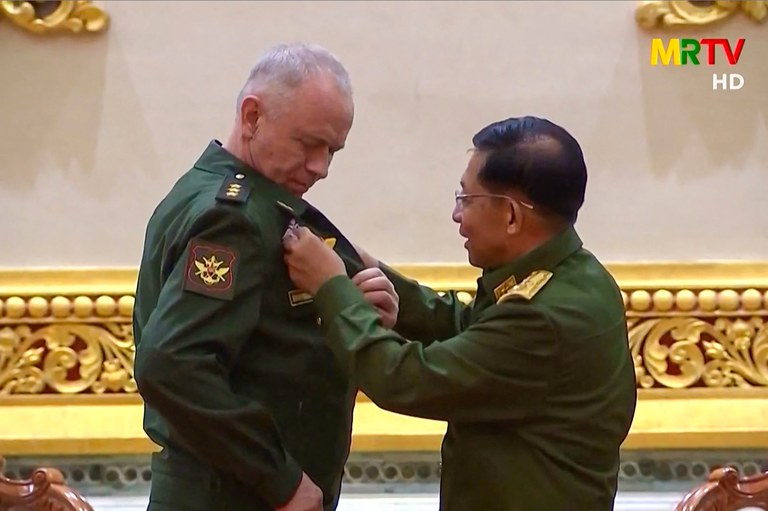 ၂၀၂၁ ခုနှစ် မတ်လ ၂၆ ရက်နေ့က စစ်ကောင်စီ MRTV ရုပ်မြင်သံကြားထုတ်လွှင့်ချက်တွင် ရုရှားဒုတိယကာကွယ်ရေးဝန်ကြီး Alexander Fomin (ဝဲ) ကို ဗိုလ်ချုပ်မှူးကြီးမင်းအောင်လှိုင်က ဆုတံဆိပ် တပ်ဆင်ပေးနေစဉ်။ (Screengrab: AFPTV)