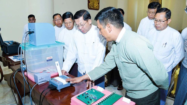 အီလက်ထရွန်နစ် မဲပေးစနစ်အသုံးပြုပုံနှင့် စက်ပိုင်းဆိုင်ရာများကို ကြည့်ရှုနေသည့် စစ်ကောင်စီဥက္ကဋ္ဌ ဗိုလ်ချုပ်မှူးကြီး မင်းအောင်လှိုင်အား ၂၀၂၃ ခုနှစ် ဖေ‌ဖော်ဝါရီလ ၉ ရက်နေ့က တွေ့ရစဉ်။ (Photo: Myanmar Military)