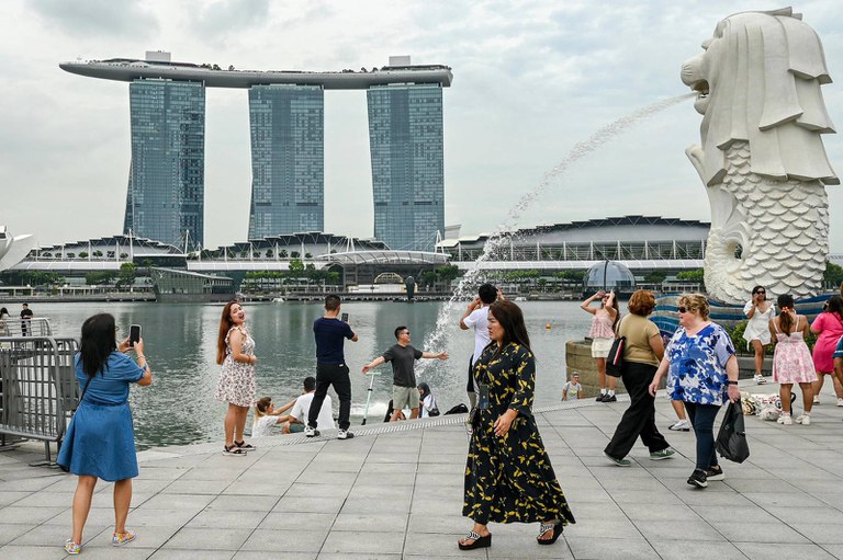 စင်ကာပူနိုင်ငံရှိ Marina Bay Sands အပန်းဖြေစခန်းရှေ့ရှိ Merlion ရုပ်တုဘေးတွင် လူတချို့အား ၂၀၂၄ ခုနှစ်၊ ဒီဇင်ဘာ ၂ ရက်နေ့က တွေ့ရစဉ်။ (Roslan RAHMAN / AFP Photo)