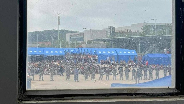 တရုတ်နိုင်ငံ မိန်းတိန်မြို့ရှိ ယာယီစခန်းတွင် စားစရာနှင့်ရေရရန် တောင်းဆိုနေသည့် မြန်မာစစ်ဘေးဒုက္ခသည်များကို ၂၀၂၃ ခုနှစ် နိုဝင်ဘာလ ၂ ရက်နေ့က တရုတ်အာဏာပိုင်များ လာရောက်ကြည့်ရှုနေစဉ်။ (Photo: Citizen Journalist)