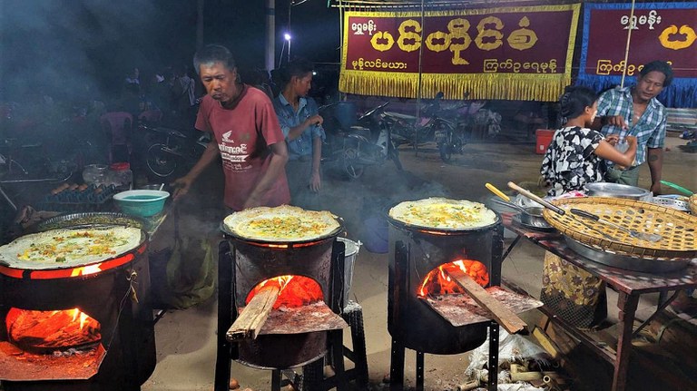 မန္တလေးတိုင်း ညောင်ဦးမြို့ ရွှေစည်းခုံဘုရားအနီးတွင် ရောင်းချနေသည့် ဆယ့်နှစ်ပွဲစျေးသည်များနှင့် ပွဲဈေးလာသူများကို  ၂၀၂၃ ခုနှစ် ဇွန်လ ၁ ရက်နေ့ညက တွေ့ရစဉ်။ (Photo: RFA)