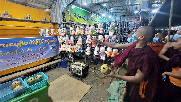 မန္တလေးတိုင်း ညောင်ဦးမြို့ ရွှေစည်းခုံဘုရားအနီးတွင် ရောင်းချနေသည့် ဆယ့်နှစ်ပွဲစျေးသည်များနှင့် ပွဲဈေးလာသူများကို  ၂၀၂၃ ခုနှစ် ဇွန်လ ၁ ရက်နေ့ညက တွေ့ရစဉ်။ (Photo: RFA)