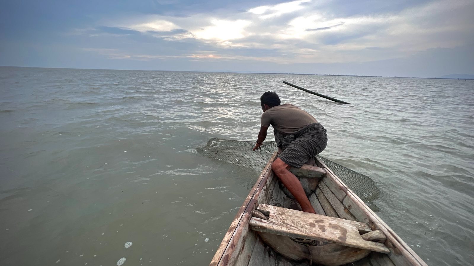 ရခိုင်ပြည်နယ်၊ စစ်တွေမြို့နယ်၊ လမ်းဘေးချောင်း ပိုက်ဆိပ် တံငါရွာတွင် ငါးဖမ်းနေသူတစ်ဦးအား ၂၀၂၃ ခုနှစ်၊ ဇွန်လ ၆ ရက်နေ့က တွေ့ရစဉ်။ (Photo: RFA)