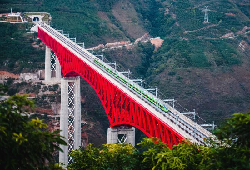中,中老铁路动车组(EMU)列车于 2021 年 12 月 3 日穿过中国云南省元江上的一座主要桥梁。中老铁路是 北京“一带一路”倡议下的数百个项目之一,这些项目旨在在亚洲、非洲和太平洋地区建设港口、铁路和其他设施。(美联社)