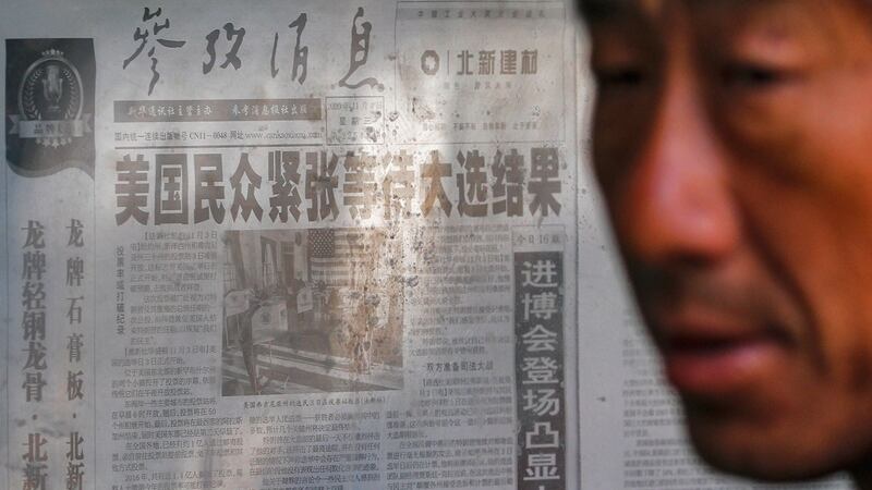 2020年11月5日,一名男子站在北京新华社官方报章头条附近,报道有关美国总统大选。(AP)