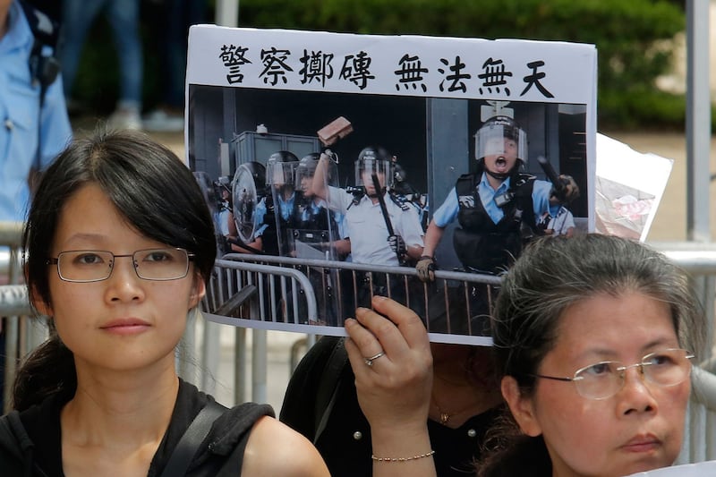 2019年6月20日,来自示威学生的父母们和宗教的各种活动团体在警察总部外抗议,示威群众举着标语牌“警察投掷砖 无法无天”。(美联社)