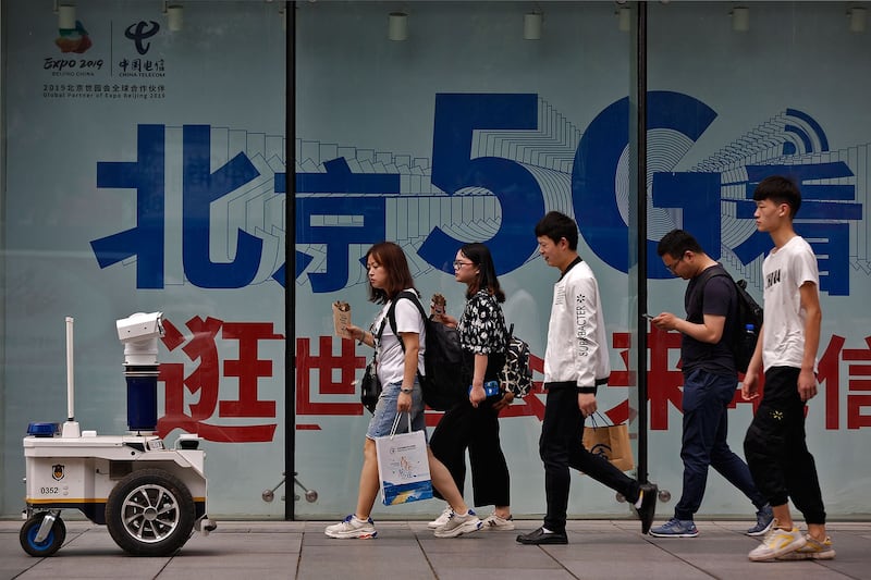 有分析却认为,中国的5G产业链尚未成熟,单靠中国一己之力去实现目标,并不现实。图为人们途经北京某购物区的5G网络广告。(资料图/美联社)