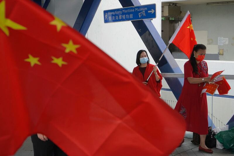 资料图片:2021 年 4 月 15 日,在香港举行国家安全教育日期间,亲中支持者向行人传递中国国旗。 (美联社)