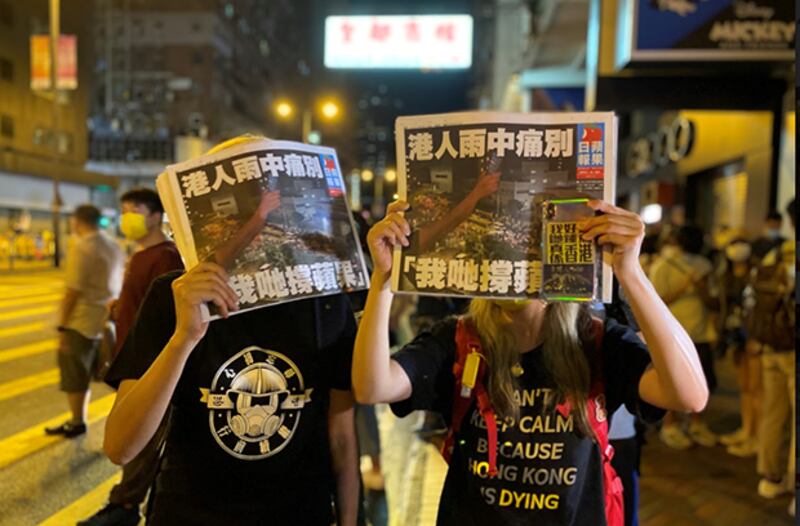 香港市民手举最后一期《苹果日报》(视频截图)