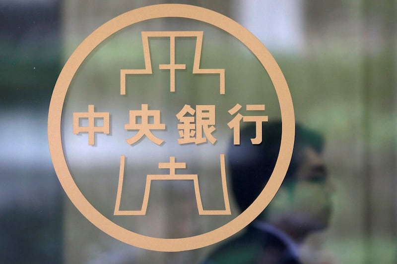 台湾经济研究院24日公布景气动向,其中台湾的5月制造业、服务业、营建业营业气候测验点同步走扬。图为,一名工作人员站在台北市台湾中央银行徽标旁。(路透社)