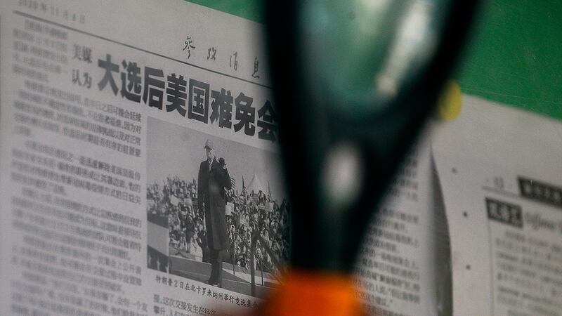 2020年11月5日,在北京,一名男子用放大镜看新华社官方报道有关美国总统大选。(AP)