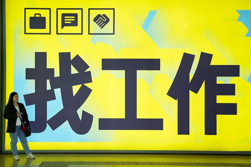 2024年7月2日,一名妇女站在北京一个地铁站张贴的"找工作"广告牌前。(美联社)