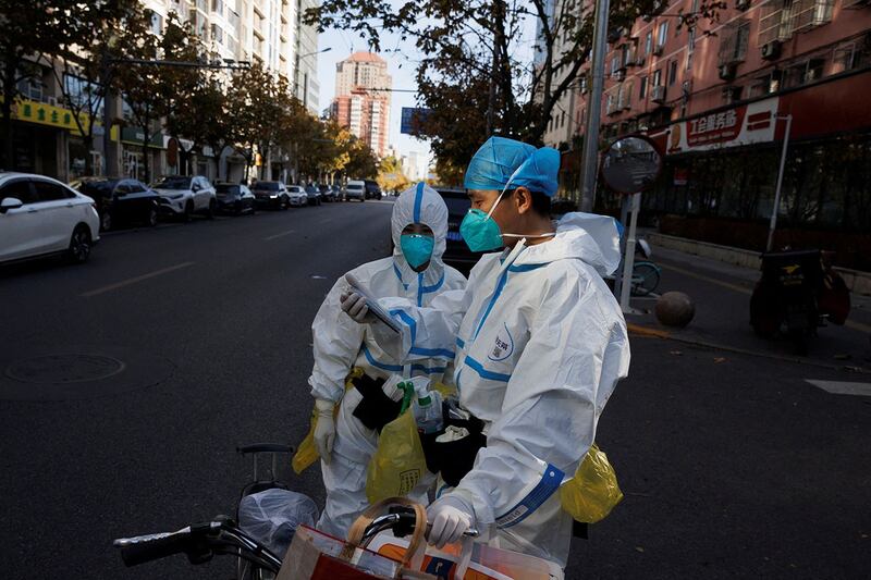 2022 年 11 月 21 日,新一波疫情也在中国各地卷土重来,防疫工作人员站在北京街上。(路透社)