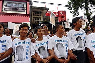 ‘ဒေါ်အောင်ဆန်းစုကြည်နှင့်အတူ...’ ဟူသော စာတမ်းပါ တီရှပ်ဆင်တူ ဝတ်ဆင်၍ နိုဝင်ဘာ ၁၂ ရက်က အမျိုးသား ဒီမိုကရေစီ အဖွဲ့ချုပ် ရုံးရှေ့တွင် ဒေါ်အောင်ဆန်းစုကြည် လွတ်လာမည်ဟု မျှော်လင့် စောင့်ဆိုင်းနေသူများ ဖြစ်ပါသည်။ (Photo: AFP)