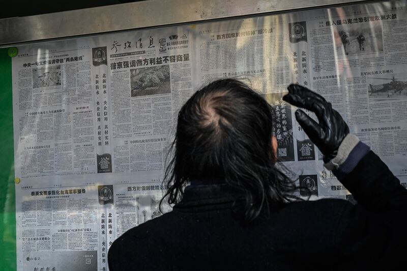 2022 年 2 月 24 日,一名男子在北京街道上阅读官方报纸。 (法新社)