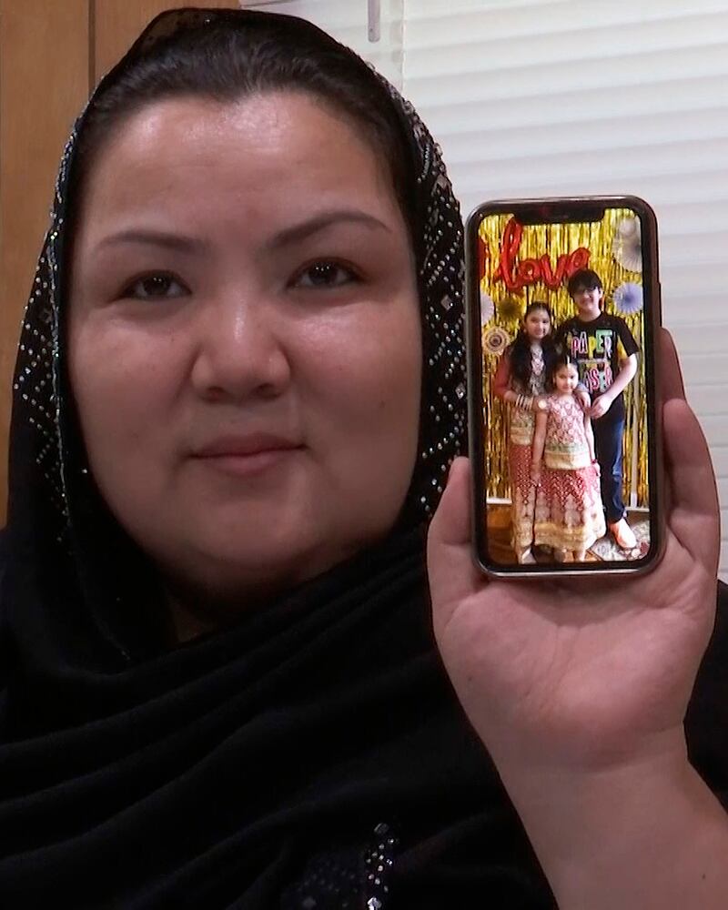 来自新疆的维吾尔人Zumret Dawut在美国弗吉尼亚的家里展示手机上她的孩子照片。(美联社)