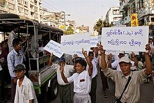 လူမှုစီးပွား ဒုက္ခများကြောင့် ၂ဝဝ၇ ခုနှစ် ဖေဖော်ဝါရီ ၂၂ရက်နေ့က ရန်ကုန် မြို့လယ်တွင် လက်ကိုင်ဆိုင်းဘုတ်များ ကိုင်ကာ ကိုထင်ကျော် (အလယ်) ဦးဆောင်၍ ကြွေးကြော် ဆန္ဒပြနေသူများကို တွေ့မြင်ရပုံ ဖြစ်ပါသည်။ (Photo: AFP)