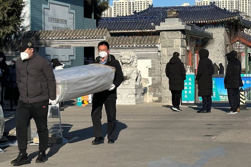 2022年12月17日,两名北京男子在火葬场外搬运棺材。(美联社)