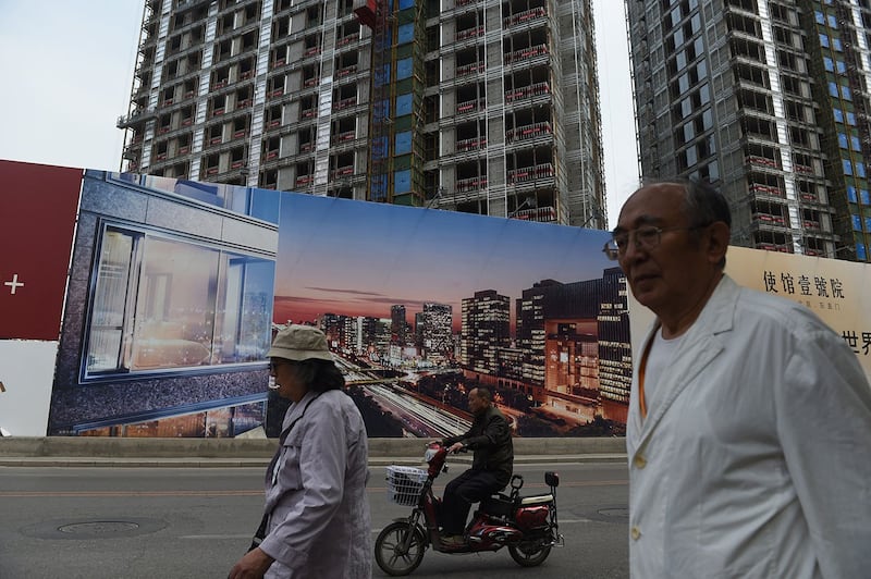 北京市民走过一处建筑工地外的新住宅区广告牌(法新社)