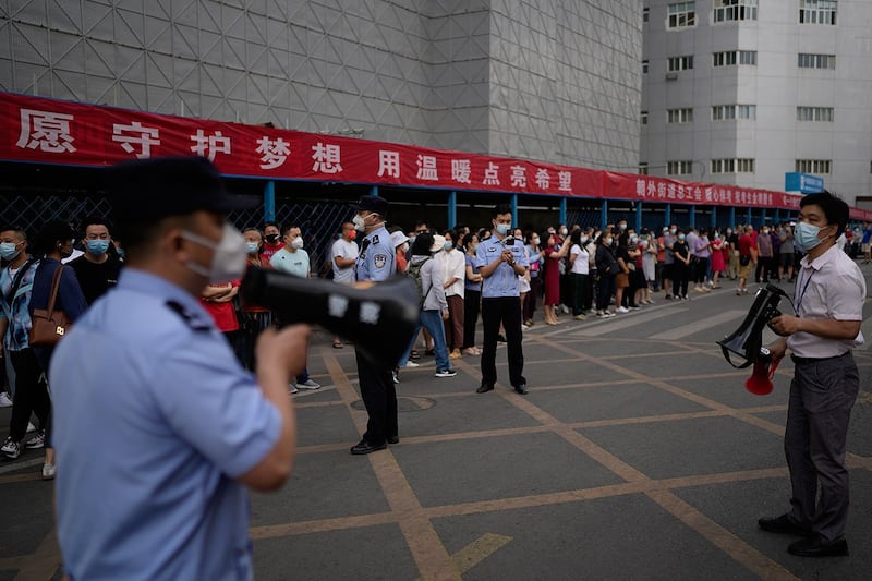 2022 年 6 月 7 日,在北京举行的中国全国高考第一天,警察,学校官员与学生家长在学校外。(美联社)