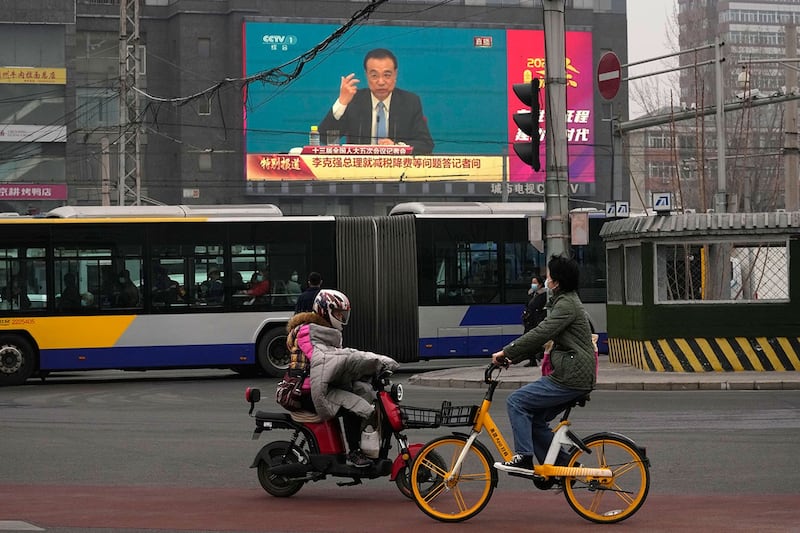 资料图片:北京,人们骑车经过十字路口的大屏幕,显示中国总理李克强在新闻发布会上的讲话。(美联社)