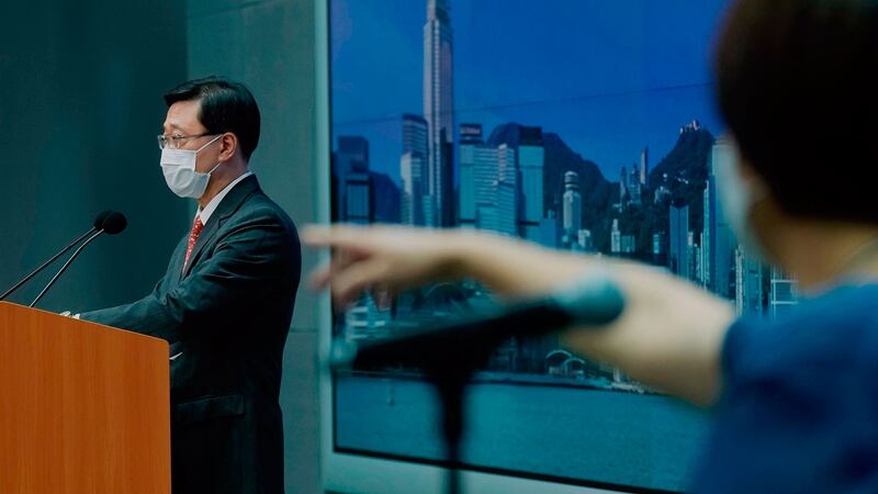 2021 年 6 月 17 日,香港保安局局长李家超(左)在新闻发布会上记者提问。 (美联社)