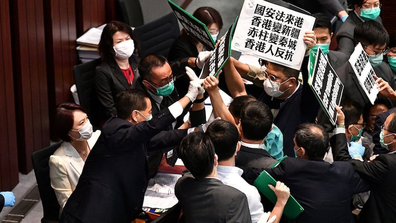 资料图片:2020年5月22日,香港立法会泛民主派议员在内务委员会的一个会议期间举牌抗议北京强推“港版国安法”,他们被保安阻拦。(法新社)