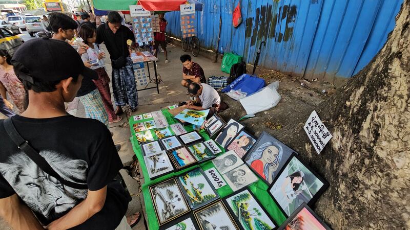 ရန်ကုန်တိုင်း၊ စမ်းချောင်းမြို့နယ်၊ မြေနီကုန်းတံတားအနီး လမ်းဘေးပလက်ဖောင်းတွင် ပုံထိုင်ဆွဲပြီး ရောင်းချပေးသည့် ပန်းချီဆရာ ဦးစိုးအောင်အား ၂၀၂၃ ခုနှစ်၊ ဒီဇင်ဘာလ ၆ ရက်နေ့က တွေ့ရစဉ်။ (Photo: RFA)
