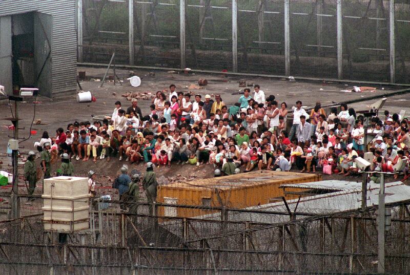 Vietnamese boat people wait at the square of the High Island detention centre as police and Correctional Services officers search for home-made weapons in the dormitory following their confrontation early June 8 morning. Police and security officers fired teargas to quell new rounds of protest at the camp and managed to re-enter the camp to remove some 94 boatpeople selected for deportation