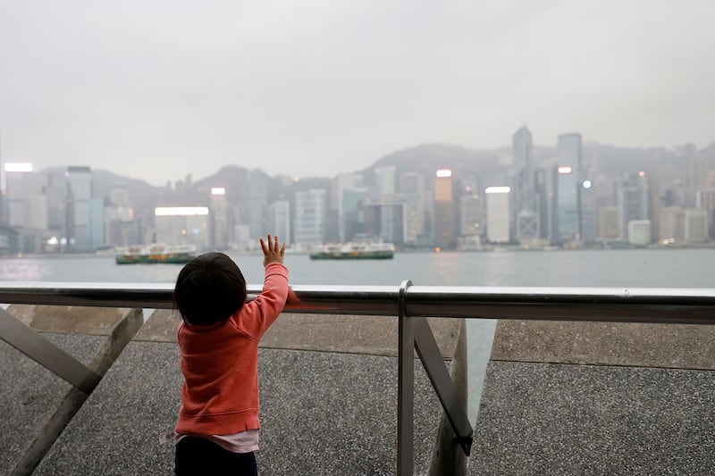 资料图片:2020 年 12 月 14 日,一岁的 Yanis Lai 与家人一起移民到苏格兰,在与家人一起来到香港尖沙咀,她向建筑物挥手告别。(路透社)