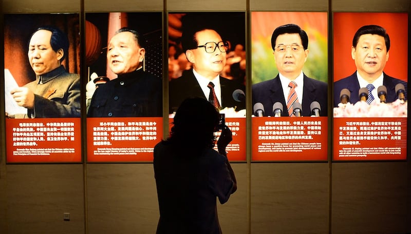 2015年7月7日,一名民众从中国五代领导人毛泽东、邓小平、江泽民、胡锦涛、习近平的画像前走过。(法新社)