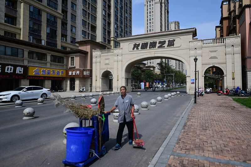 2023年6月20日,一名环卫工人站在河南省郑州市新郑市一栋未完工公寓楼入口前。(法新社)