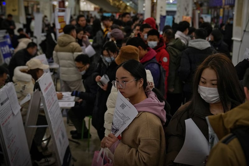 2024年2月23日,求职者在北京的招聘会上拿着宣传册寻找职位空缺。(美联社)