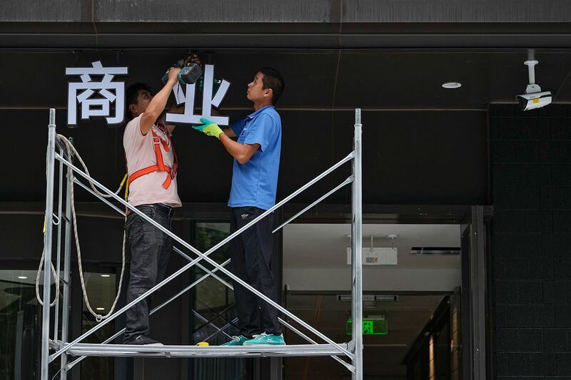 2024年7月15日,工人从脚手架上将写有"商业"字样的牌匾安装到北京一栋正在装修的商业办公楼上。(美联社)