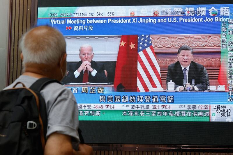 2022年7月29日,一名男子在香港一家购物中心观看电视播出的习近平和拜登通话的新闻。(路透社)