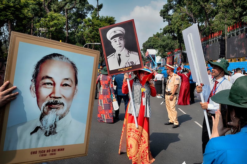A woman holds a portrait of Vietnamese Gen. Vo Nguyen Giap as another holds a photo of the late Vietnamese revolutionary leader Ho Chi Minh, left, after a parade celebrating the 50th anniversary of the end of the Vietnam War, April 30, 2025, in Ho Chi Minh City, Vietnam.