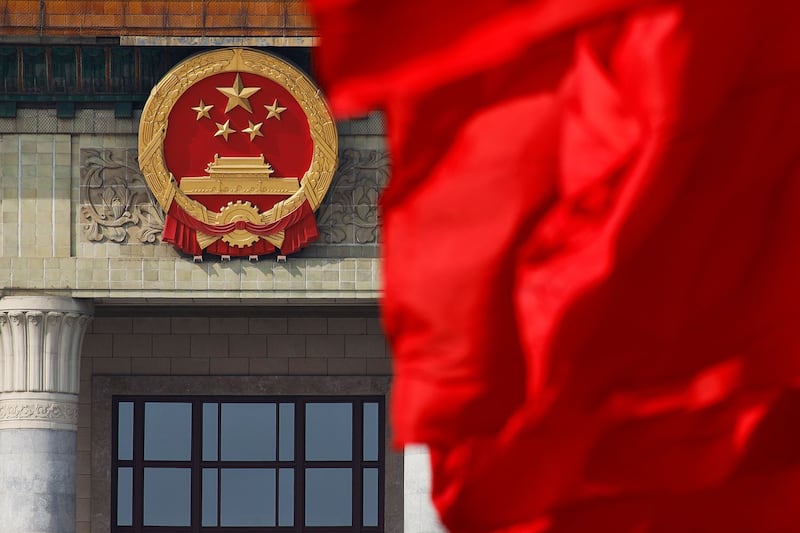 中国人大常通过《反外国制裁法》,学者警告北京别高估自己实力。图为,北京人民大会堂外的中国国徽附近,红旗飘扬。 (美联社图片)
