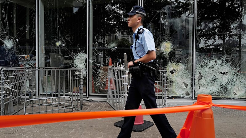 一名香港警察走过被破坏的立法会大楼外面。(美联社)