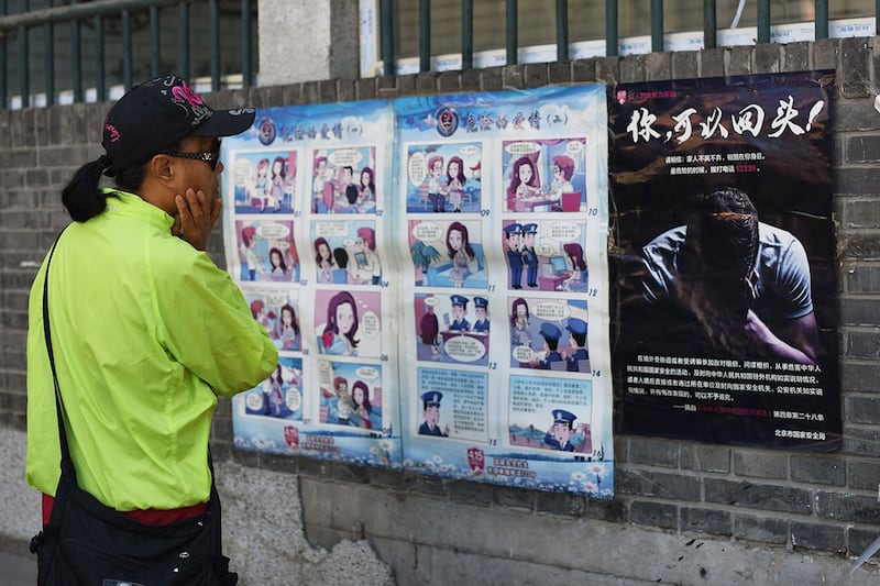 在北京的街头墙上粘贴的警告当地居民注意外国间谍的宣传漫画和海报。(法新社)