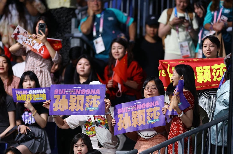 2024年8月3日,中国选手陈梦在巴黎奥运乒乓球女单决赛中对阵队友孙颖莎,多名观众举牌为孙颖莎加油。(路透社)