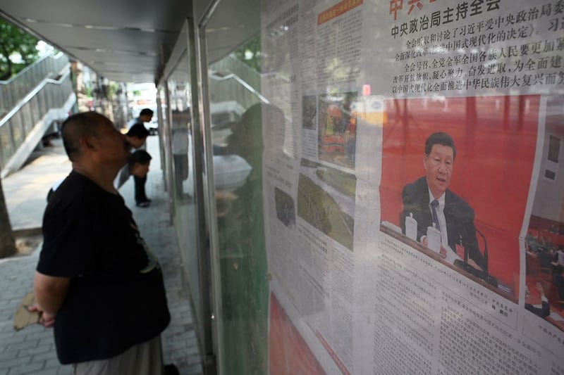 2024年7月19日,一名男子在北京街道上的展示板前阅读中共三中全会的相关报道。(法新社)
