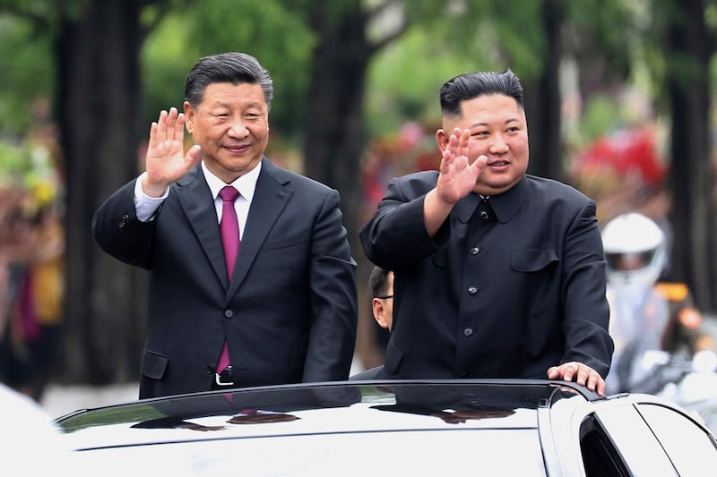 资料图: 2019年6月20日,访问平壤的中国国家主席习近平与朝鲜领导人金正恩共同乘坐迎宾礼车,对民众挥手致意。(Xinhua via AP, File)