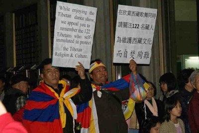 ཐེ་ཝན་དུ་རྒྱ་ནག་ཀན་སུའུ་ཞིང་ཆེན་མི་རིགས་གླུ་གར་ཚོགས་པ་ཞེས་བས་སྐོར་བསྐྱོད་འཁྲབ་སྟོན་སྐབས་བོད་མིས་ངོ་རྒོལ་བྱེད་བཞིན་པ། ཐེ་ཝན་དུ་རྒྱ་ནག་ཀན་སུའུ་ཞིང་ཆེན་མི་རིགས་གླུ་གར་ཚོགས་པ་ཞེས་བས་སྐོར་བསྐྱོད་འཁྲབ་སྟོན་སྐབས་བོད་མིས་ངོ་རྒོལ་བྱེད་བཞིན་པ།